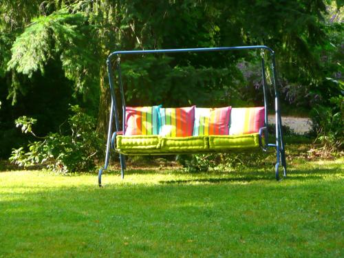 a swing sitting in the grass in a yard at Chambres d'hôtes et Roulotte Au Bonheur Du Parc in Le Breuil