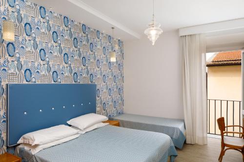 a bedroom with two beds and a blue wall at Hotel Del Corso in Sorrento