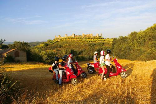 a group of people riding scooters on a field with a castle at Villa Fiorenzani in Radicondoli