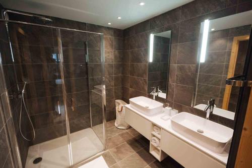 a bathroom with a shower and two sinks and a glass shower stall at Megeve Appartment – Vacances d'hiver – АЕ102 in Megève