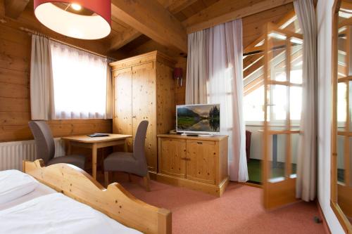 um quarto com uma cama, uma televisão e uma secretária em Aparthotel Alpin Life em Sankt Anton am Arlberg