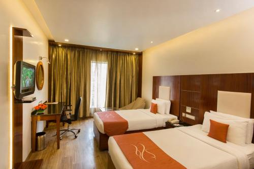 a hotel room with two beds and a desk at Citrine in Bangalore