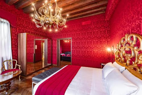 a red bedroom with a large bed and a chandelier at Palazzo San Lorenzo in Venice