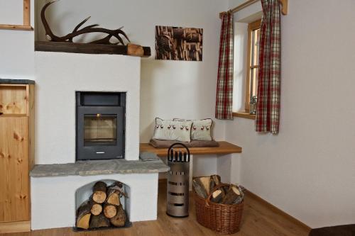 a living room with a fireplace with logs in it at Rainbachhütte-Waldgut Granig in Glödnitz