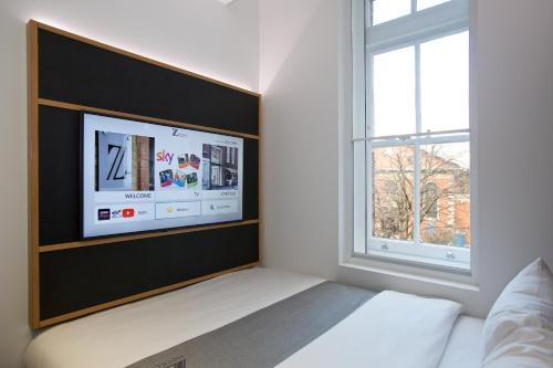 a bedroom with a bed with a tv on the wall at The Z Hotel Covent Garden in London
