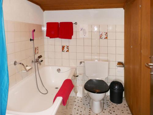 a bathroom with a toilet and a bath tub with a red towel at Alba in Saas-Fee