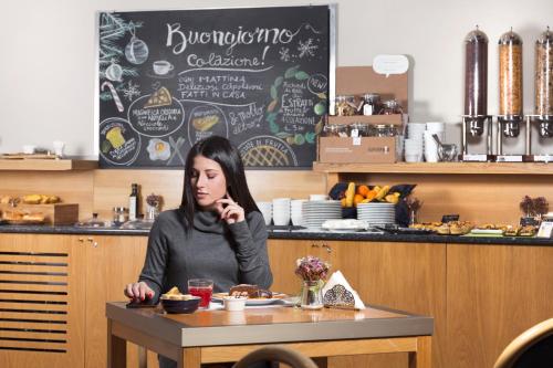 a woman sitting at a table in a restaurant at City Hotel & Suites in Foligno