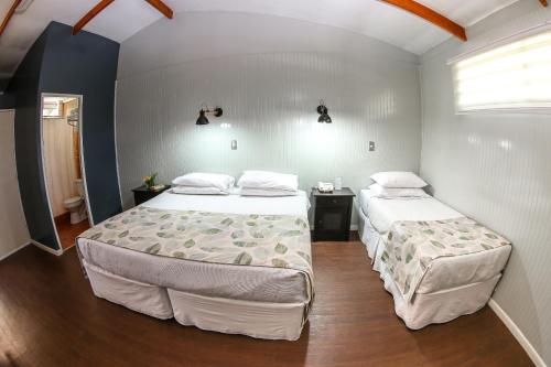 a bedroom with two beds and a table and a window at Easter Island Ecolodge in Hanga Roa