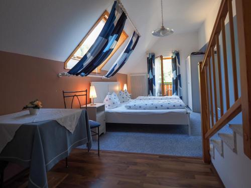 Schlafzimmer mit einem Bett, einem Tisch und Fenstern in der Unterkunft Landgasthof Zum Schwarzen Grat in Isny im Allgäu