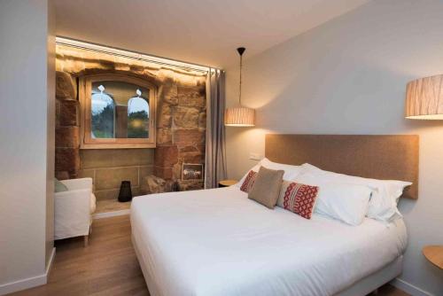 a bedroom with a large white bed and a stone wall at Heredad de Unanue in Donostia-San Sebastián