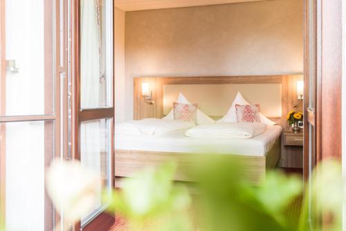 a bedroom with a bed with white sheets and pink pillows at Hotel Stegner in Rödelsee