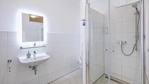 a white bathroom with a sink and a shower at Boutique-Hotel Kronenstuben in Ludwigsburg