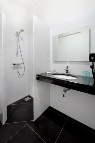 a white bathroom with a sink and a mirror at Slaap bij TRIX in Arnhem