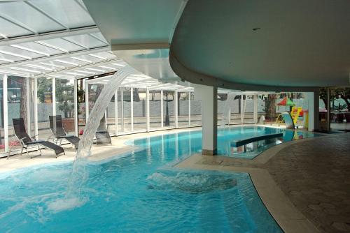 a swimming pool with a waterfall in a building at Hotel Globus, Sure Hotel Collection by Best Western in Milano Marittima