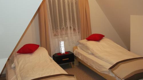 two beds with red pillows in a small room at Apartamenty Lejówka in Chochołów