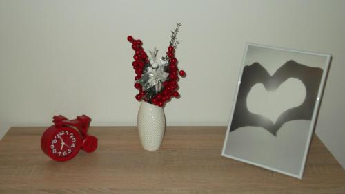 a white vase with flowers and a clock on a table at Apartamenty Lejówka in Chochołów