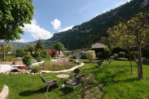 a garden with chairs and a table in the grass at Logis Hotel L'Embarcadère in Nantua