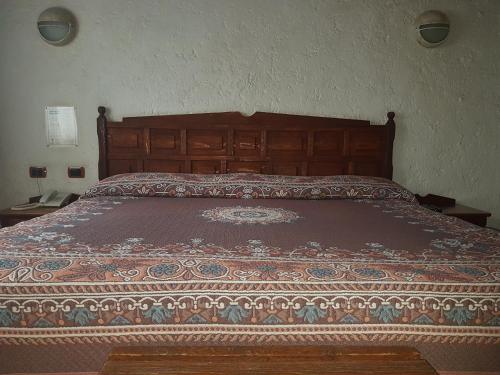a bedroom with a bed with a wooden head board at State Inn in Chihuahua