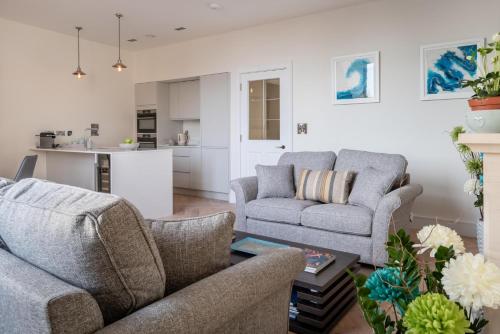 a living room with two couches and a kitchen at Cathedral View - An Exclusive Private Apartment on Cathedral Green, Exeter in Exeter