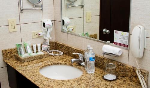 a bathroom sink with a hair dryer and a phone at Rincon del Valle Hotel & Suites in San José