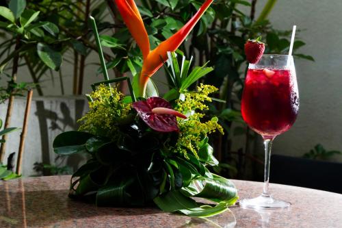 a vase of flowers next to a glass of wine at Rincon del Valle Hotel & Suites in San José
