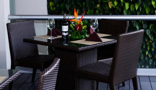 a table with a bottle of wine and two glasses at Rincon del Valle Hotel & Suites in San José