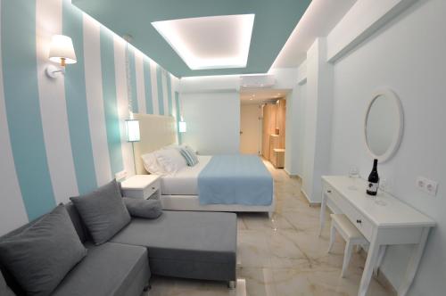 a room with a bed and a couch and a mirror at Agios Gordios Beach Resort in Agios Gordios