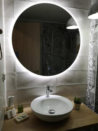 a bathroom with a sink and a round mirror at Sali Boutique hotel in Alexandroupoli