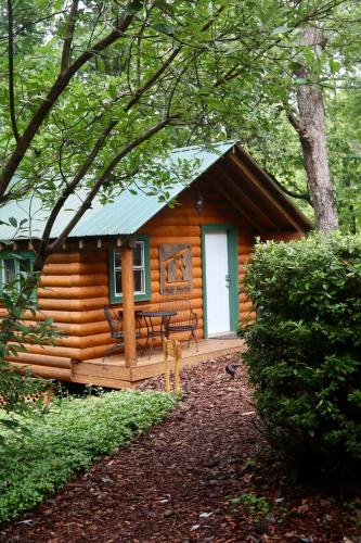 a log cabin with a porch and a white door at Barefoot Hills in Dahlonega