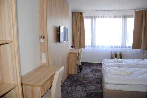 a hotel room with two beds and a desk at Hotel Labe in Pardubice