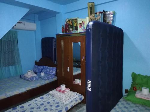 a room with two beds and a large blue refrigerator at Arlleane Sidney's Relaxation Home Big Family Blue Room in Manaoag