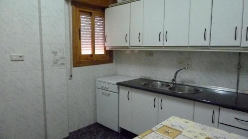 a kitchen with white cabinets and a sink at Apartamentos Casa FERMINA - A 2 horas de las pistas de esquí in Trevélez