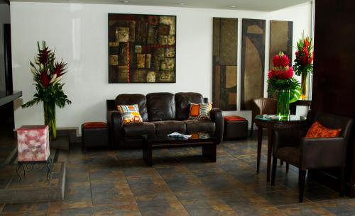 a living room with a leather couch and a table at Rincon del Valle Hotel & Suites in San José