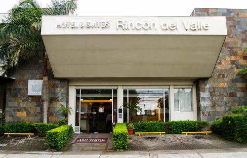 a building with two benches in front of a building at Rincon del Valle Hotel & Suites in San José