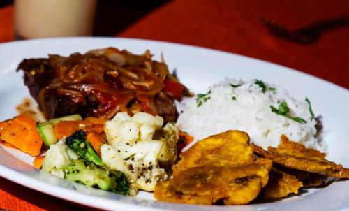 a plate of food with rice and meat and vegetables at Rincon del Valle Hotel & Suites in San José