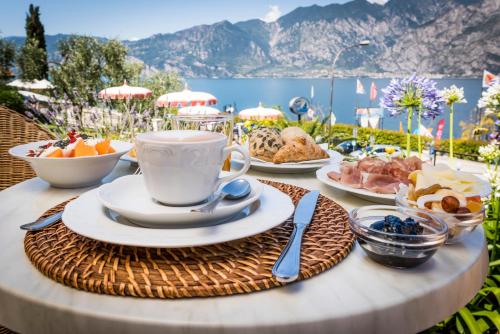 a table with a cup of coffee and a plate of food at Hotel Oasi Beach in Malcesine