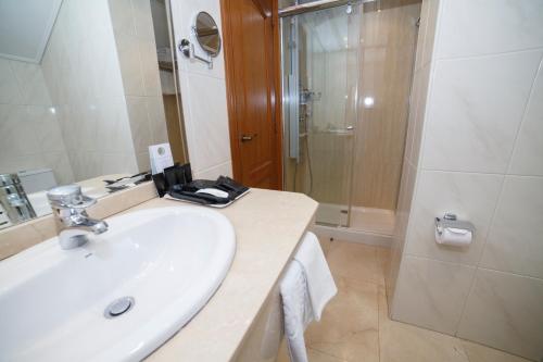 a white bathroom with a sink and a shower at Hotel Hoyuela in Santander