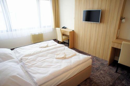 a hotel room with a white bed and a desk at Hotel Labe in Pardubice