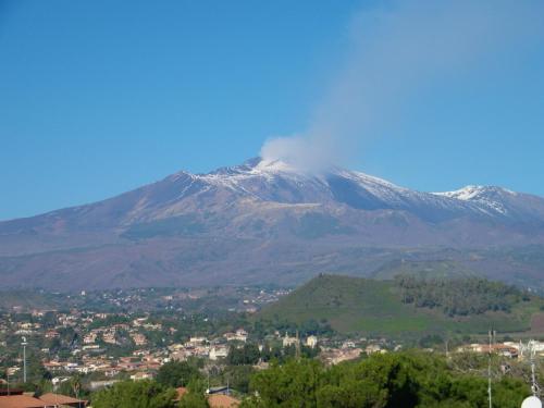 a snow covered mountain with a town in front of it at B&B La Casetta in Aci Bonaccorsi