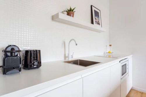 a white kitchen with a sink and a microwave at Joie Paris Porte Maillot - Palais Des Congrès in Neuilly-sur-Seine