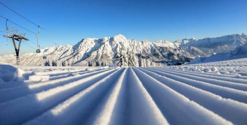 a snowy road with snow covered mountains in the background at Appartements Spielberg in Leogang