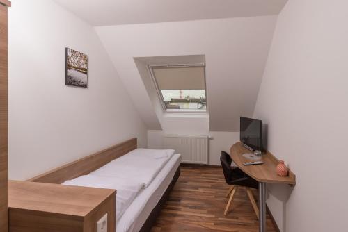 a small bedroom with a bed and a desk with a computer at Boutique-Hotel Kronenstuben in Ludwigsburg