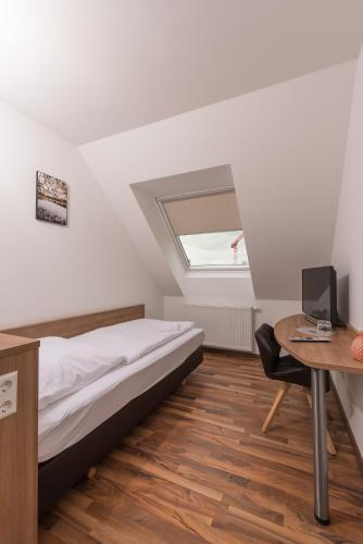 a bedroom with a bed and a desk with a computer at Boutique-Hotel Kronenstuben in Ludwigsburg