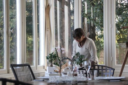 a woman is sitting at a table with flowers at La maison au fil du temps in Pont-Rémy