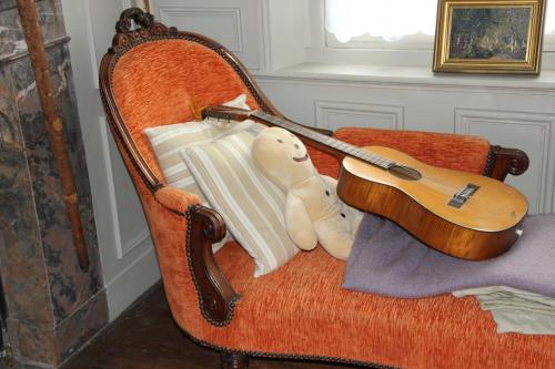 a teddy bear sitting on a chair with a guitar at La maison au fil du temps in Pont-Rémy