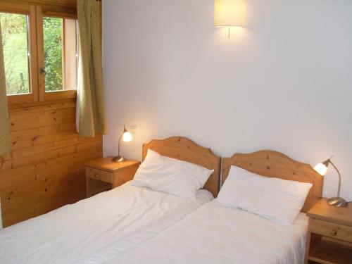 um quarto com 2 camas com lençóis brancos e 2 candeeiros em Spacious Apartment 2 Minutes from Ski Lift, Equipped for Babies em Les Houches