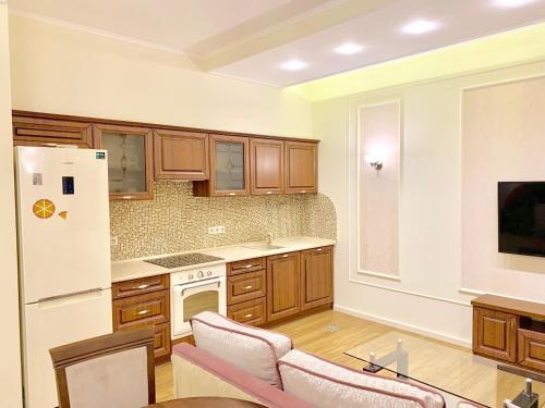a kitchen with wooden cabinets and a white refrigerator at Two-bedroom on Lesi Ukrainky in Lviv