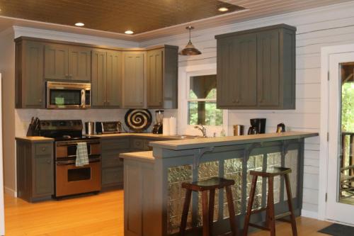 a kitchen with gray cabinets and a island with bar stools at Barefoot Hills in Dahlonega