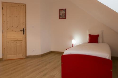 a red and white bed in a room with a door at Gîtes de l'Orée du Bois - Boussières in Boussières
