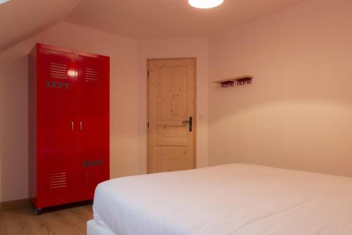 a bedroom with a red cabinet and a white bed at Gîtes de l'Orée du Bois - Boussières in Boussières